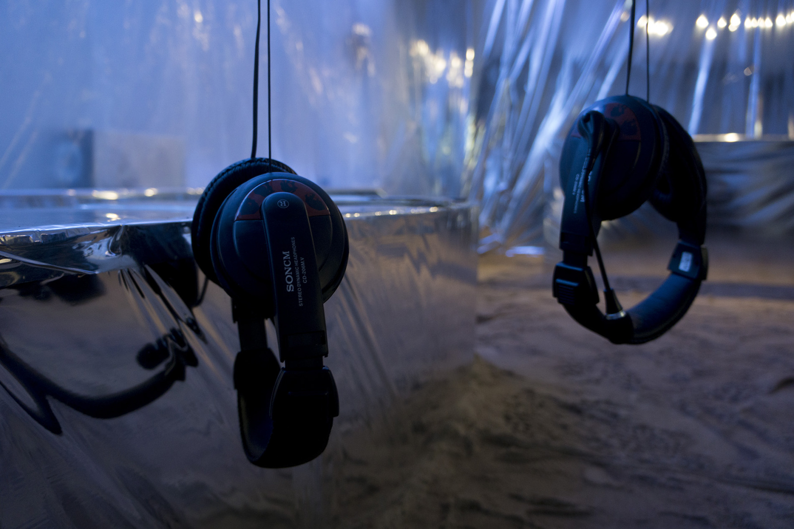 Headphones hanging from the tree inside the installation Headphones hanging from the tree inside the installation